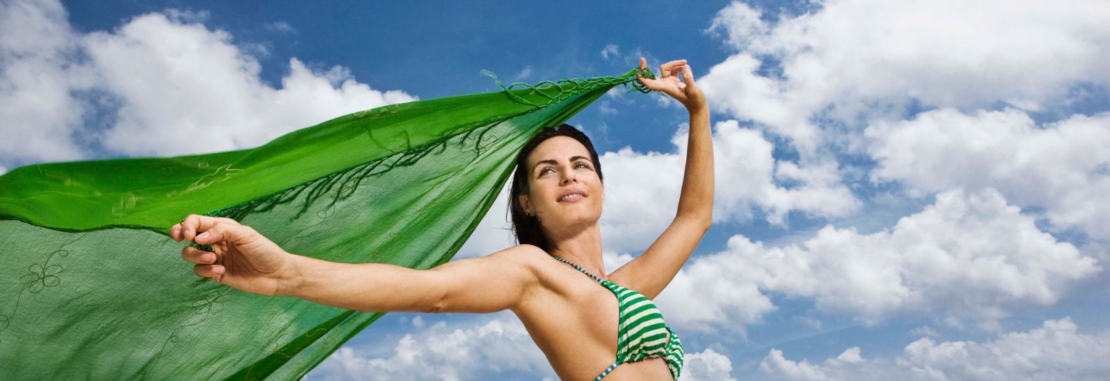 A woman in a bikini holding onto a green cloth