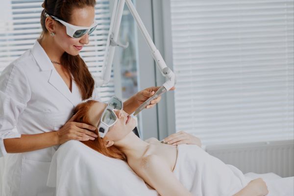 A woman is getting her face waxed by an esthetician.