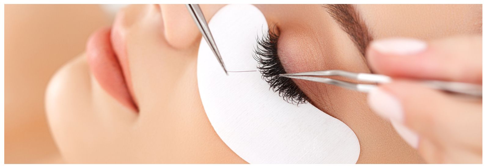 A person is holding some scissors and putting on their lashes.